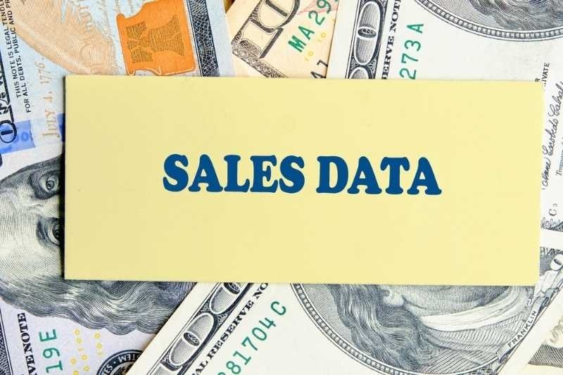 Sales data label placed over U.S. dollar bills.