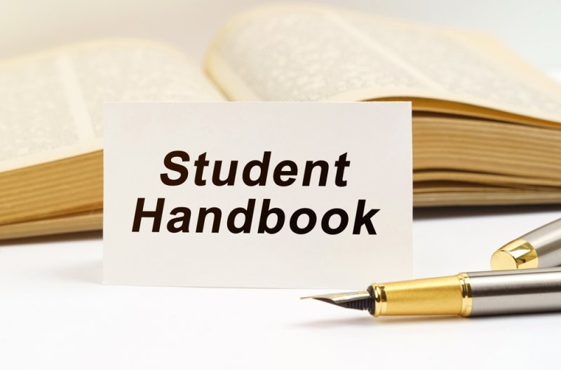 Education concept. Against the background of the book lies a pen and a business card with the inscription - Student Handbook