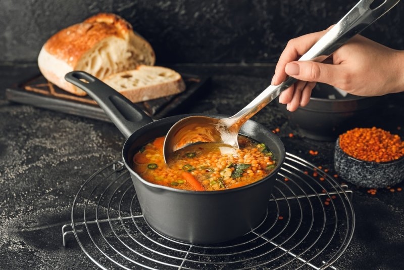 Female hand with saucepan of hot lentil soup
