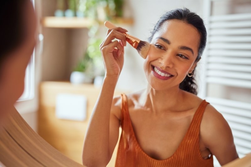 girl applying makeup using powder brush