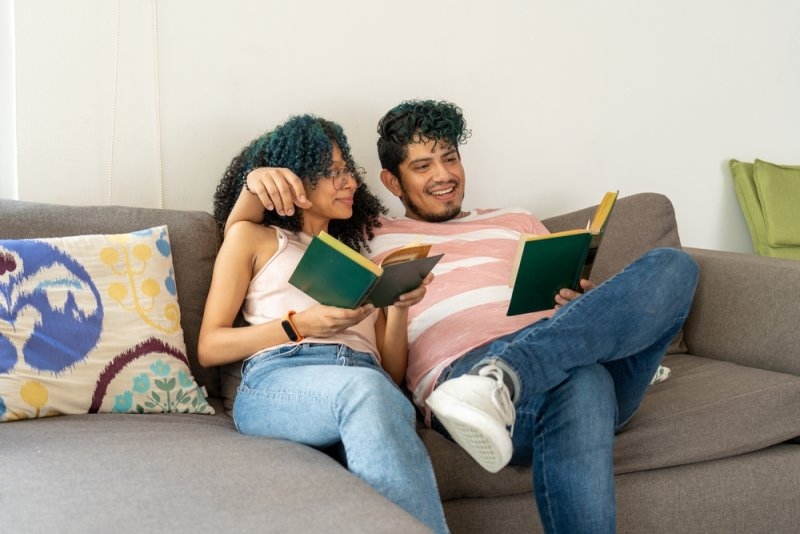 Happy couple sitting on a sofa reading book