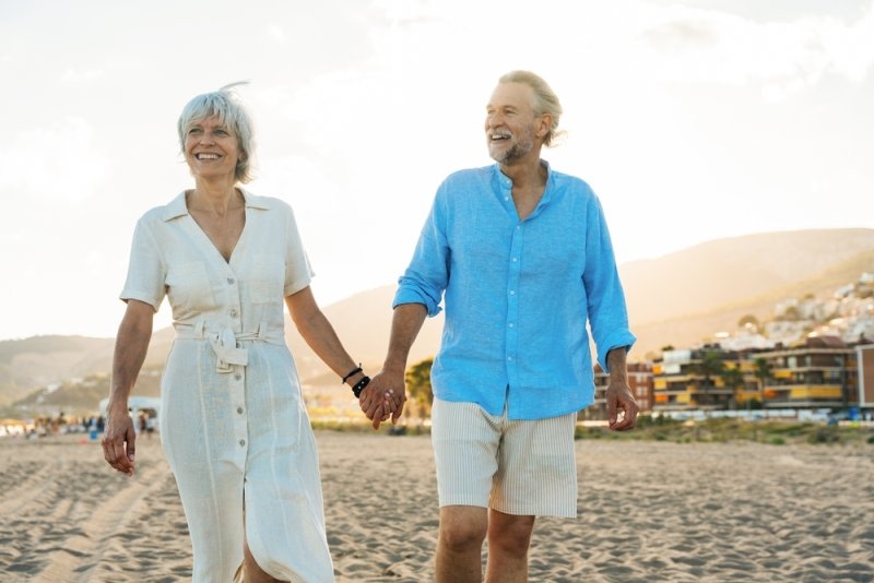 Senior happy couple walking on the beach holding hands