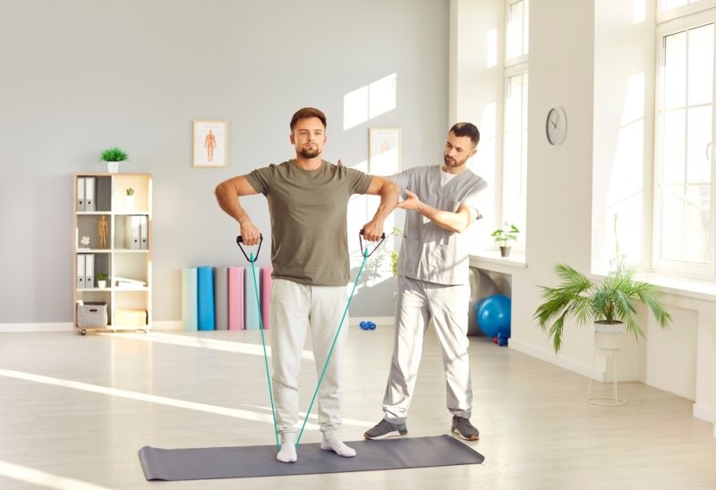 Physical therapist giving therapy to a man at his home