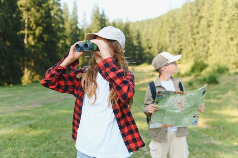 Kids enjoying summer camp exploring nature using binoculars and map
