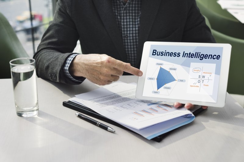 Man holding a tablet with business intelligence text and data on screen