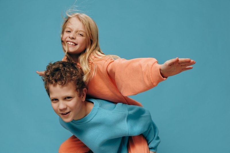 a boy and a girl, play and the brother rides his sister on his back.