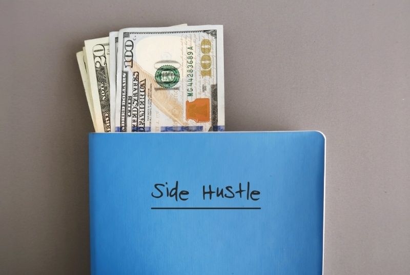 Envelope labeled ‘Side Hustle’ with US dollar bills inside, symbolizing extra income.