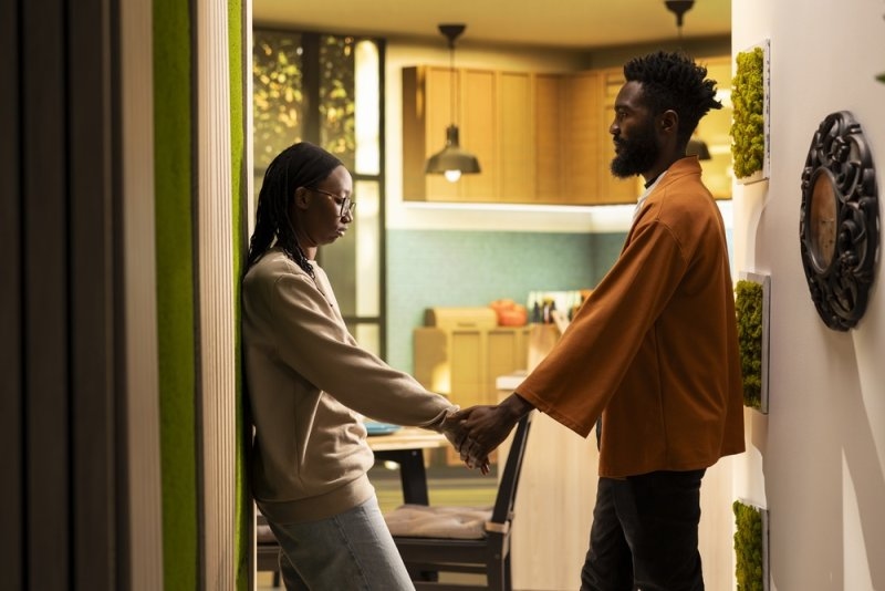 A couple holding hands while appearing emotionally disconnected.