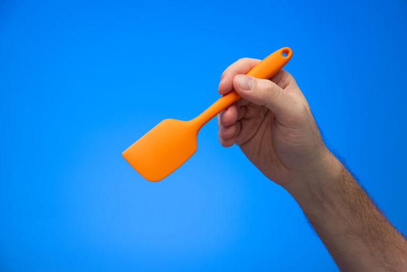 hand holding an orange silicone spatula