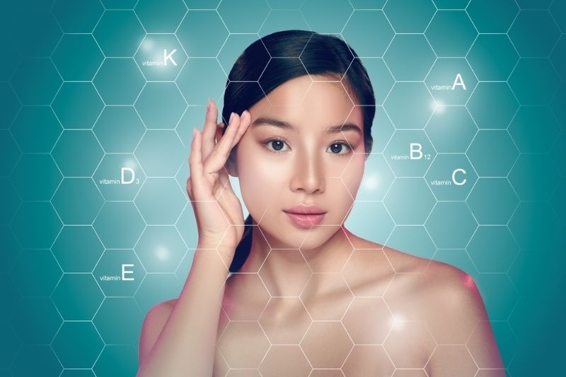 Woman showcasing skincare benefits with vitamins highlighted on her skin.