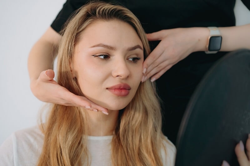 makeup artist holding face and showing glow on woman face