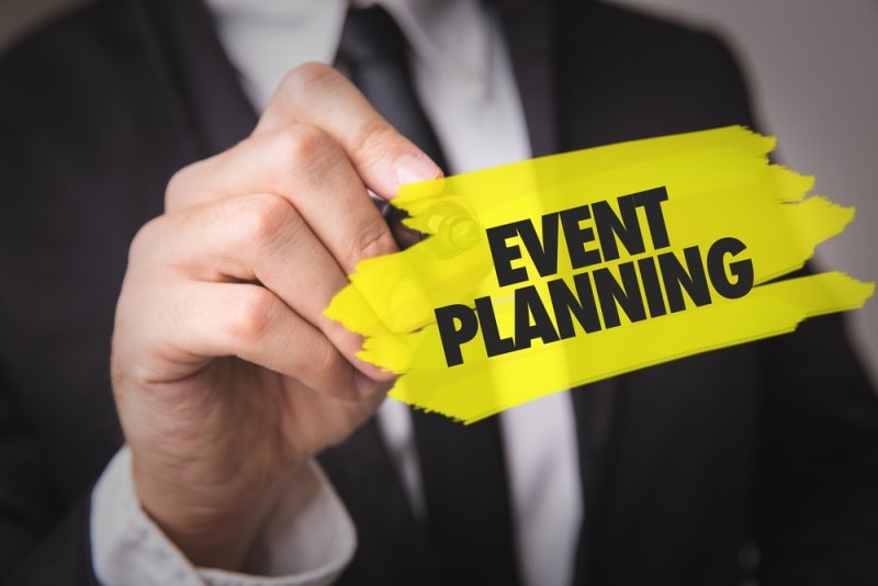 Business professional writing “EVENT PLANNING” on a bright yellow graphic.
