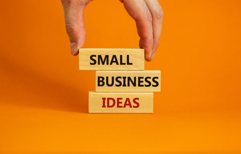 Wooden blocks spelling “SMALL BUSINESS IDEAS” stacked against an orange background.