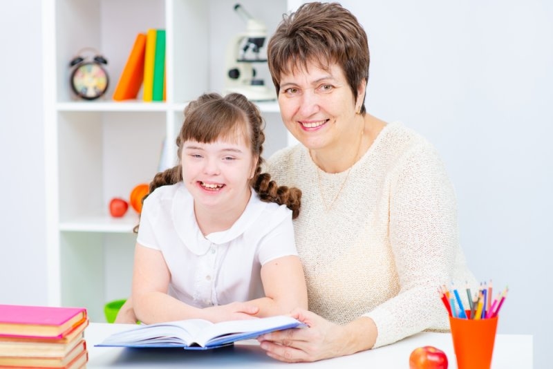 A teacher supporting a student with learning activities in a classroom setting.