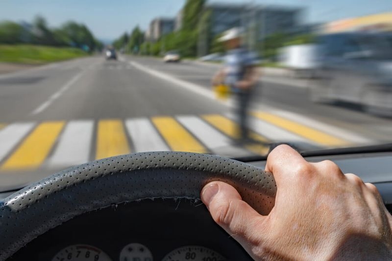 The driver hand on the steering wheel of a car moving at high speed