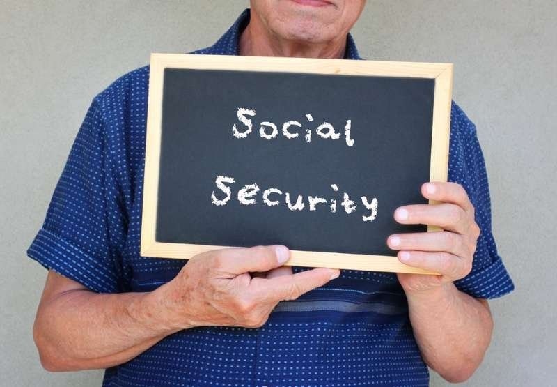 senior man holding blackboard with the phrase social security written on it.