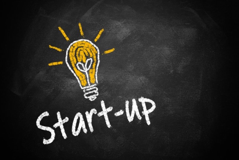 Start up text with a glowing bulb drawing on black board