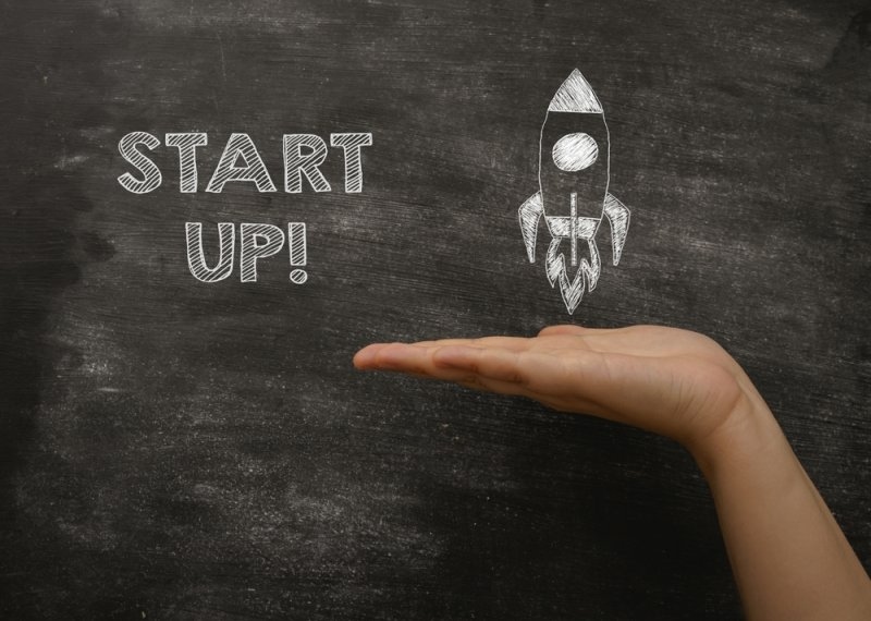 Start up text on a  black board with rocket drawing