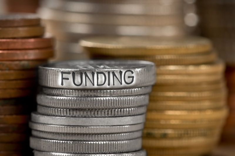 Stacks of coins with the word ‘Funding’ engraved on top, representing financial investment.