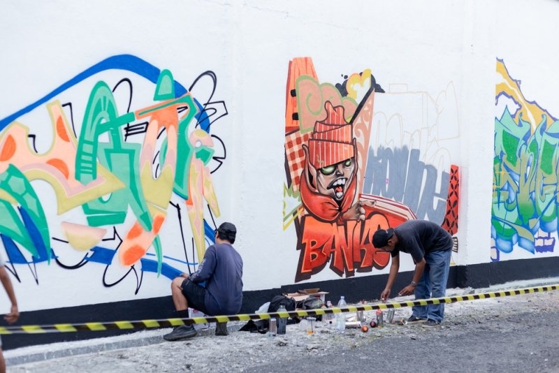 Artists creating colorful graffiti murals on a wall.
