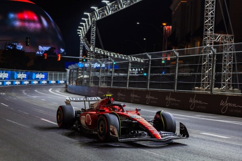 Ferrari Formula 1 car racing at night on the Las Vegas street circuit surrounded by illuminated barriers and city infrastructure.