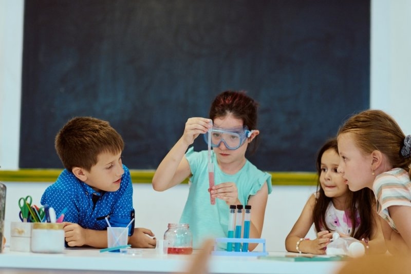 Children conducting a science experiment in a classroom, wearing safety goggles and learning together