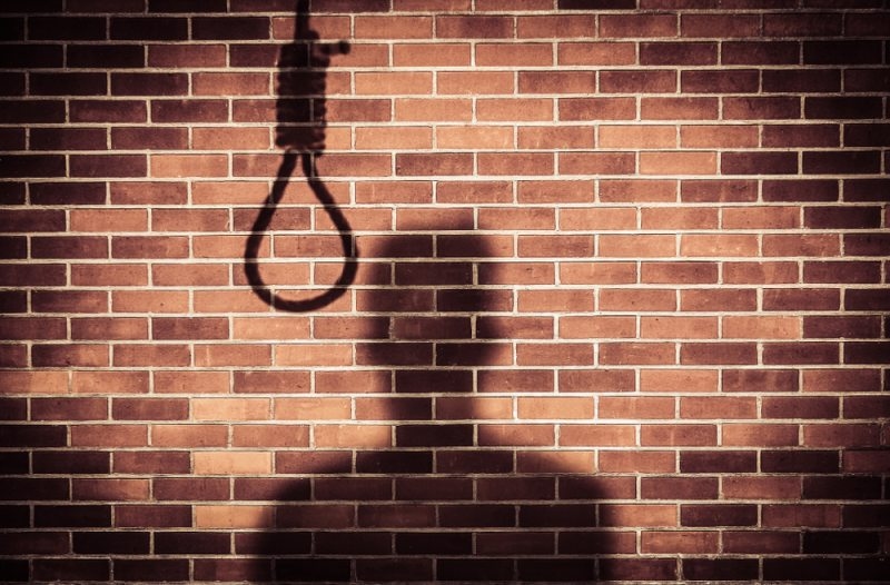 shadow of a sad man with hangman noose on wall