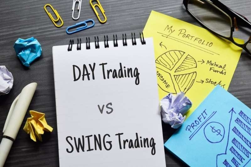 Notebook labeled ‘Day Trading vs Swing Trading’ beside investment notes and office supplies.
