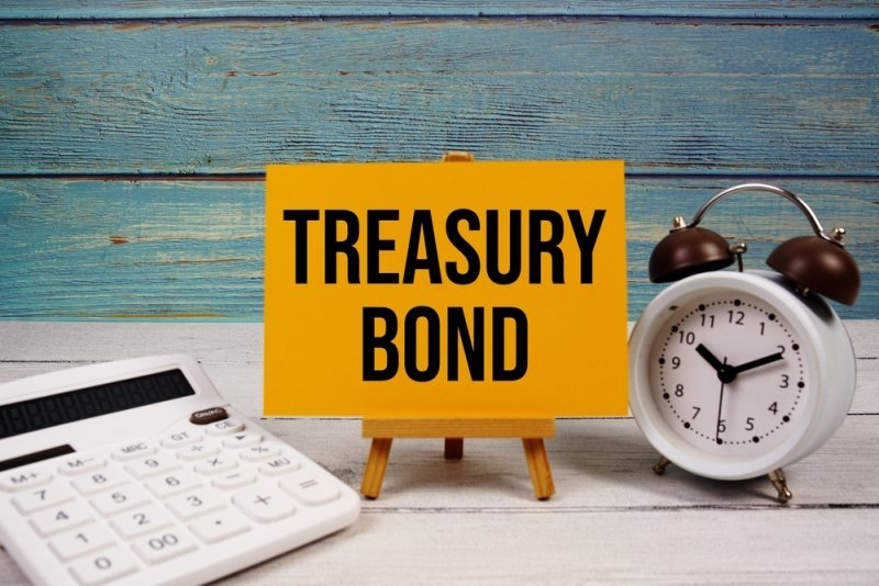 Treasury Bond text written on paper card with calculator and alarm clock