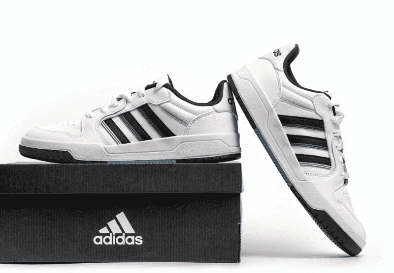 Pair of white and black Adidas sneakers displayed on top of a branded shoebox against a clean white background.