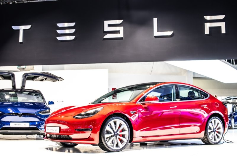 A red Tesla model and Tesla logo upside with black background