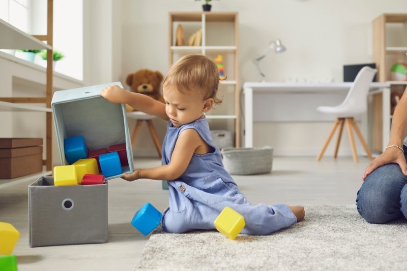 Toddler boy putting toys away