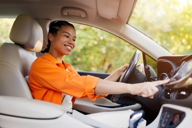 Smiling woman driving a modern car with her hands on the steering wheel.