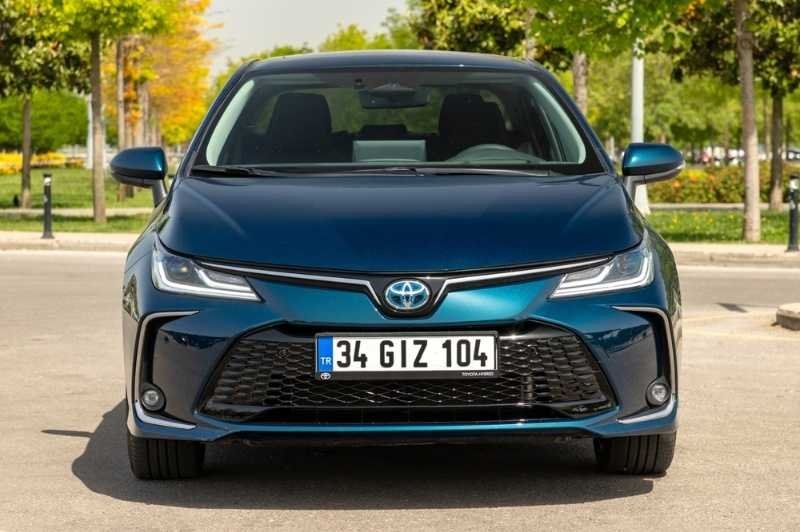 Front view of a blue Toyota sedan parked outdoors on a tree-lined street in daylight.