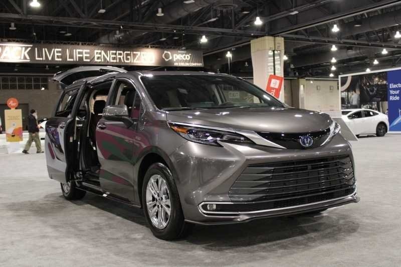 Gray Toyota Sienna minivan displayed at an indoor auto show with its sliding doors open, showcasing family-friendly vehicle features.