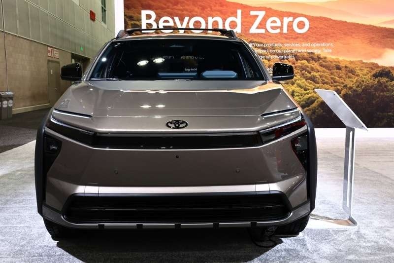 Front view of a Toyota electric SUV displayed indoors at an auto show with 'Beyond Zero' branding in the background.