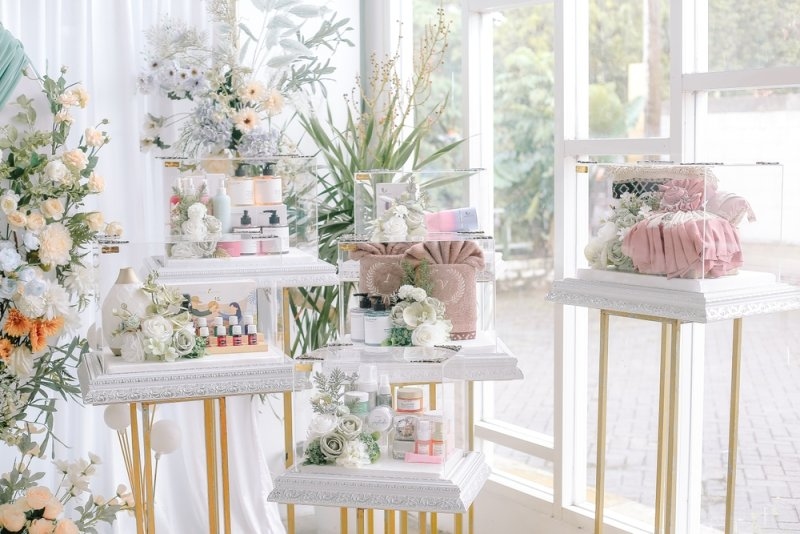Elegant wedding gifts and decorative items displayed on white tables at a wedding celebration.