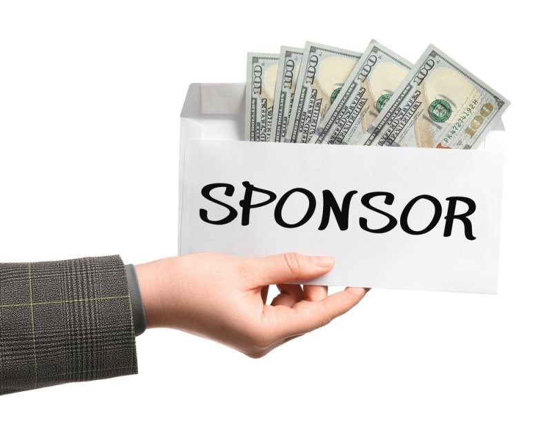 A hand holding an envelope labeled “SPONSOR” containing cash.