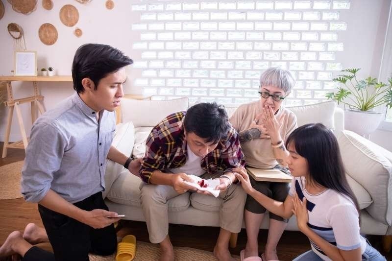 Family gathered around a sick person at home, showing concern and support during illness or medical distress.