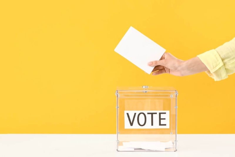 woman putting a voting card in a box labelled vote