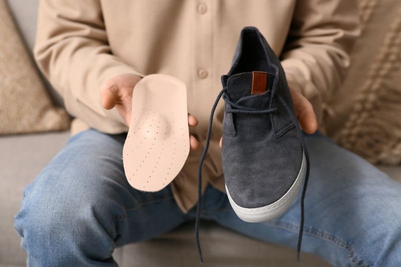 man holding a shoe and its sole