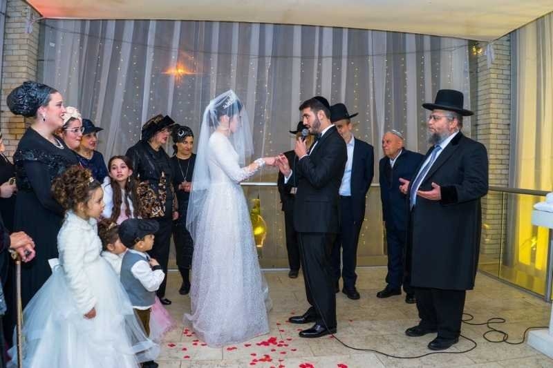 A bride and groom participate in a wedding ceremony surrounded by family and guests.