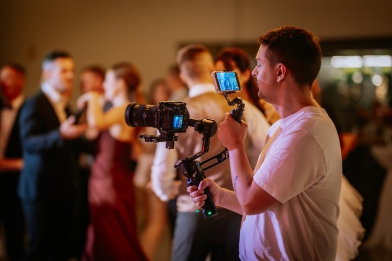 Videographer recording a wedding reception with a professional camera and handheld gimbal.