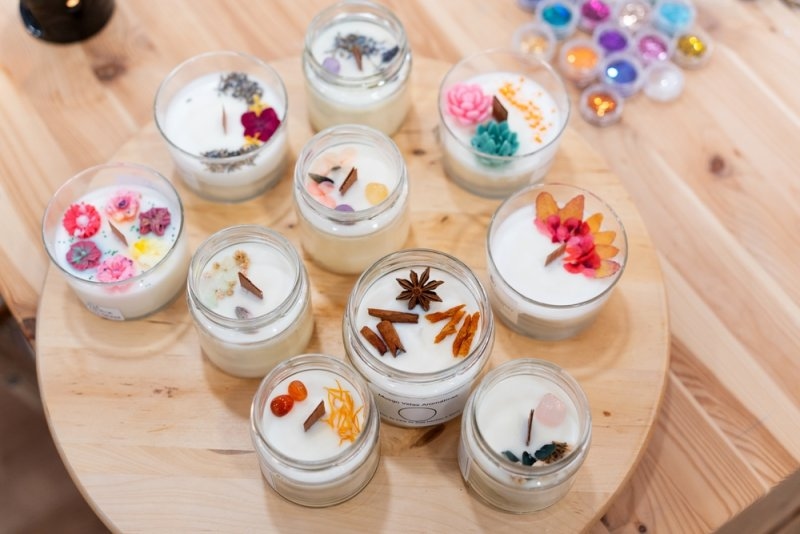 Variety of natural soy candles prepared during a workshop, decorated with dried flowers, herbs, and spices.