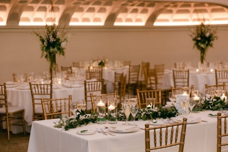 Wedding reception with elegantly arranged tables, white tablecloths, and gold chairs for organized guest seating.