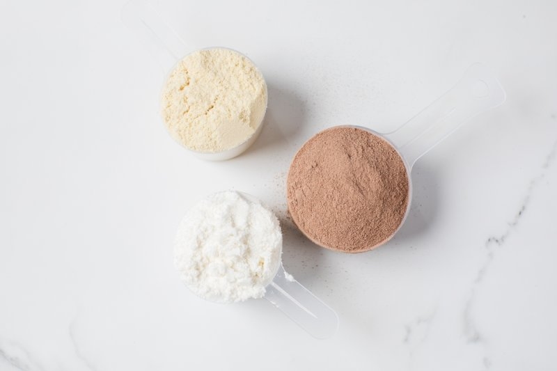 Various protein powders in scoops on grey background