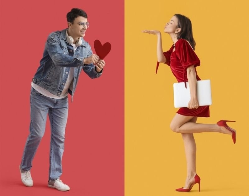 Young man with heart and pretty woman blowing kiss on color background.