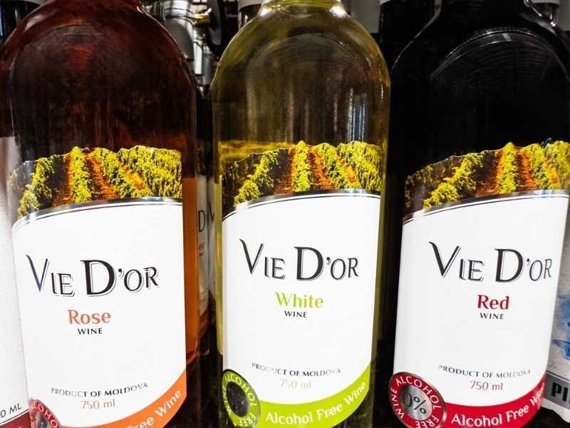 Assorted red, white, and rosé wine bottles displayed with vineyard-themed labels.