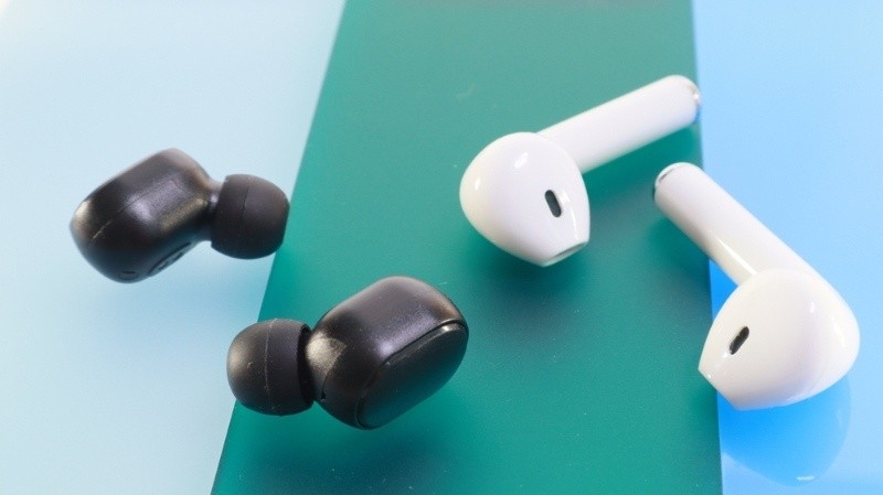 Black and white wireless earbuds placed on a colorful surface, showing two different styles of earphones.