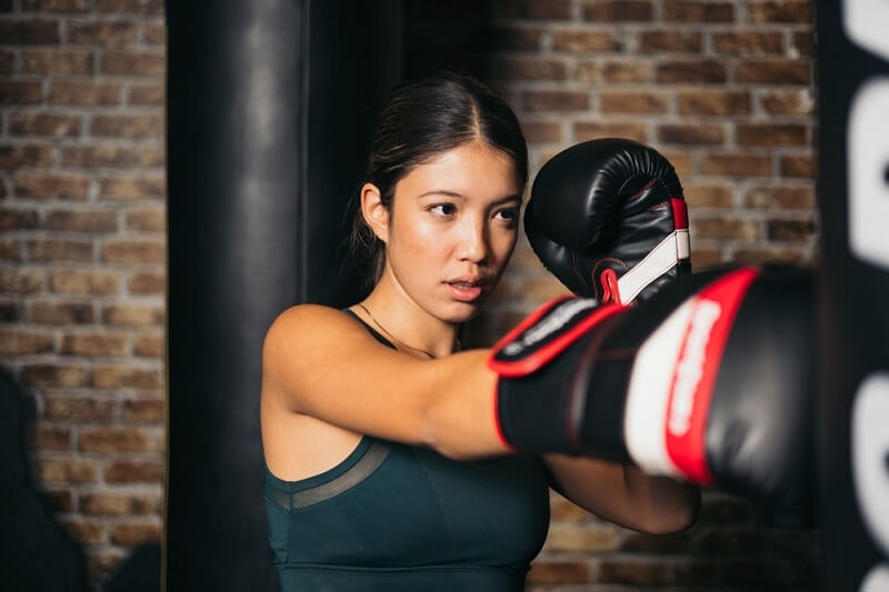 woman japanese boxer practicing on punching bag